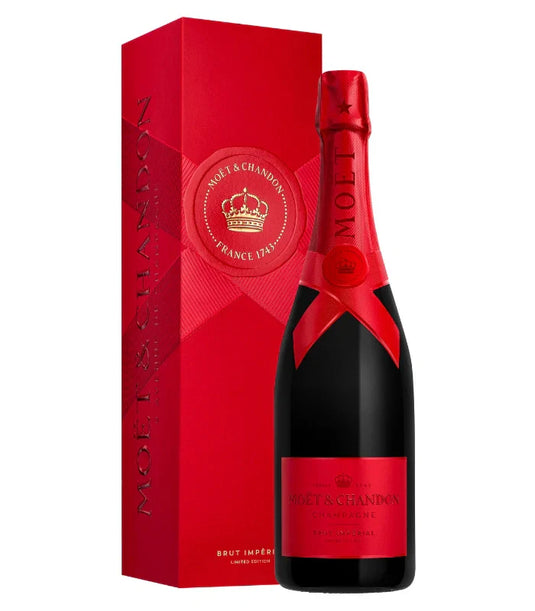 A bottle of Möet & Chandon Imperial Brut Red Holiday 2025 Limited Edition with a red foil top and label stands beside a matching red box featuring the Möet & Chandon logo and gold crown.
