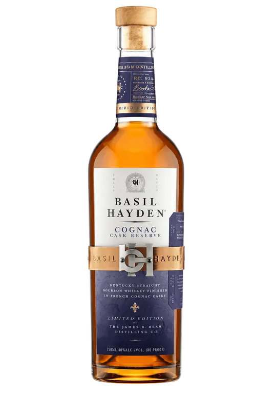 A bottle of Basil Hayden Cognac Cask Reserve whiskey, featuring a white and navy blue label with a gold band, filled with amber liquid and sealed with a cork, on a light gray background.