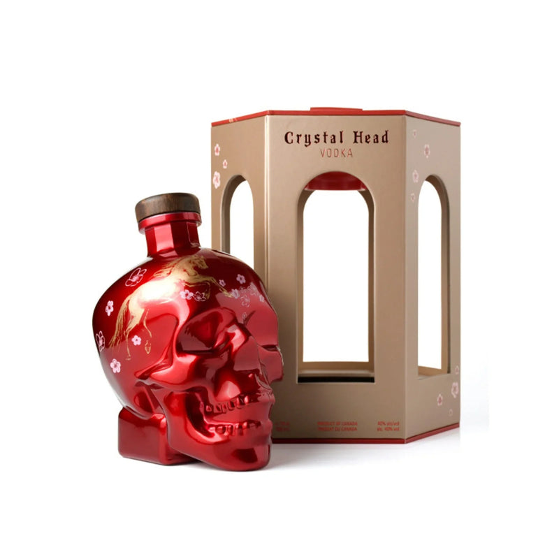 Load image into Gallery viewer, A shiny red Crystal Head Vodka Year of the Horse 2026 Lunar New Year Limited Edition skull bottle with floral designs and a wooden cap stands by a beige-and-red box with cut-out windows, both displayed on a white background.

