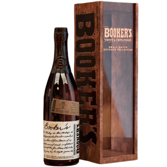 A bottle of Booker’s Batch 2026-02 “Milkshake Batch” Kentucky Straight Bourbon Whiskey with a handwritten-style label stands beside its tall wooden case, featuring a clear front and bold “BOOKER’S” branding—an uncut, unfiltered bourbon.