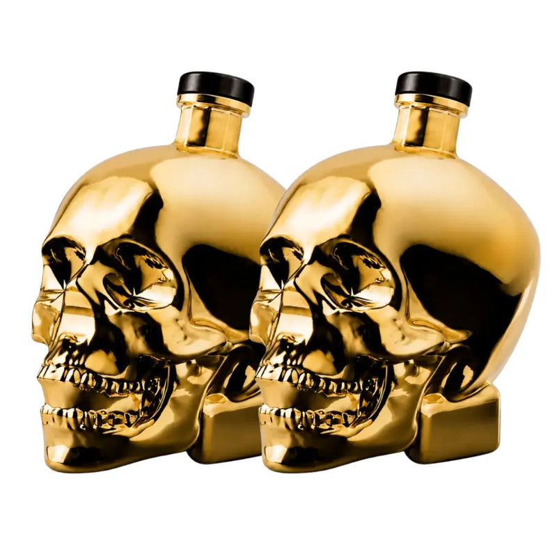Load image into Gallery viewer, Two gleaming gold bottles shaped like human skulls with black caps, positioned side by side on a white background, highlight the bold design of Crystal Head Vodka Gold Edition (Pre-Order) by Crystal Head Vodka—a premium Canadian spirit celebrated for its unique style and outstanding quality.

