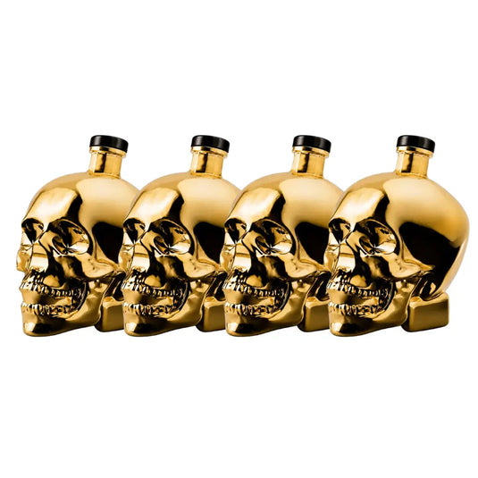 Four gleaming bottles of Crystal Head Vodka Gold Edition (Pre-Order) by Crystal Head Vodka, each featuring a skull-shaped design and finished with black caps, are neatly lined up on a white background, highlighting the product’s striking appearance and premium Canadian vodka inside.