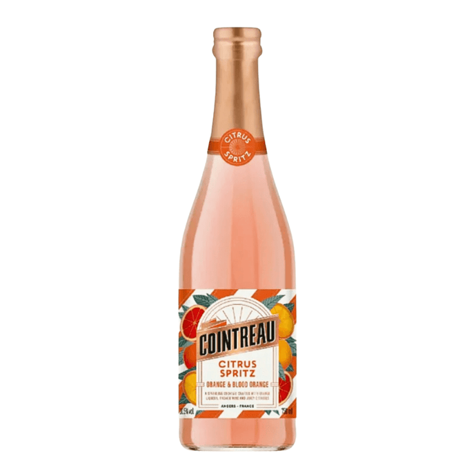 A bottle of Cointreau Citrus Spritz Orange & Blood Orange features a pink-orange liquid, orange and gold label with citrus fruit illustrations, a copper cap, and bears the Cointreau brand name.