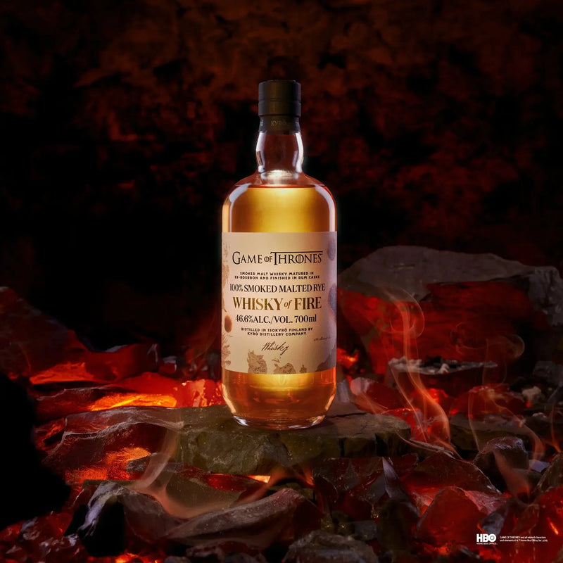 Load image into Gallery viewer, A bottle of Kyrö x Game of Thrones Whisky of Fire &amp; Blood Bundle from Main Street Liquor stands on glowing coals amid swirling smoke, with a fiery backdrop—an epic tribute to Finnish rye whisky craftsmanship. Pre-order now!.
