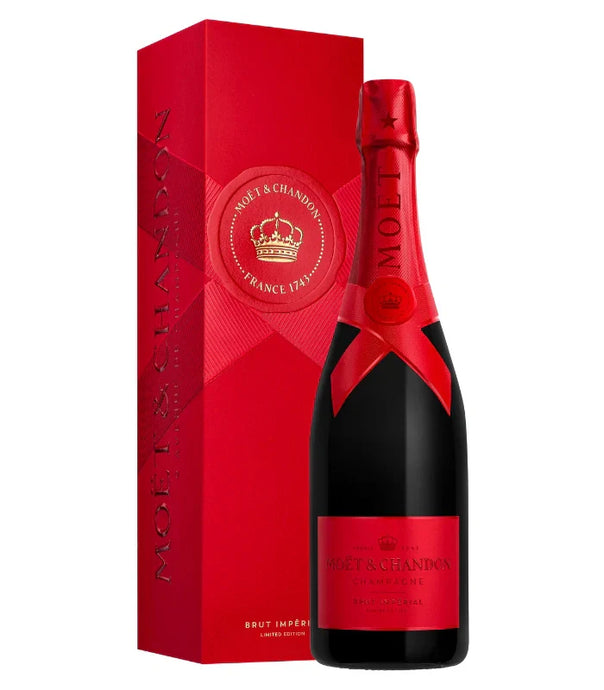 A bottle of Möet & Chandon Imperial Brut Red Holiday 2025 Limited Edition with a red foil top and label stands beside a matching red box featuring the Möet & Chandon logo and gold crown.