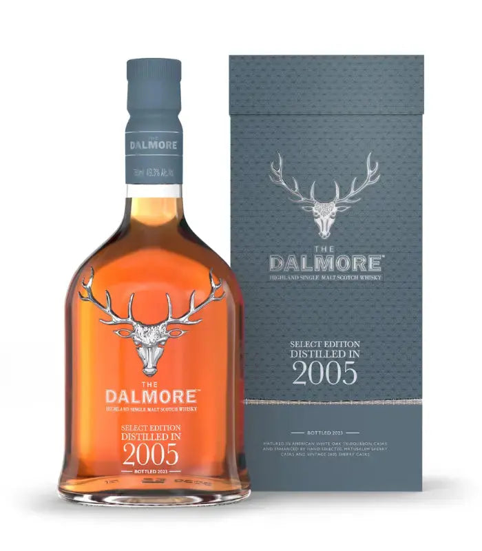 Load image into Gallery viewer, A bottle of The Dalmore Select Edition Distilled in 2005 stands before its coordinating blue-gray box, each emblazoned with The Dalmore’s silver stag logo and white lettering highlighting the product name and vintage.
