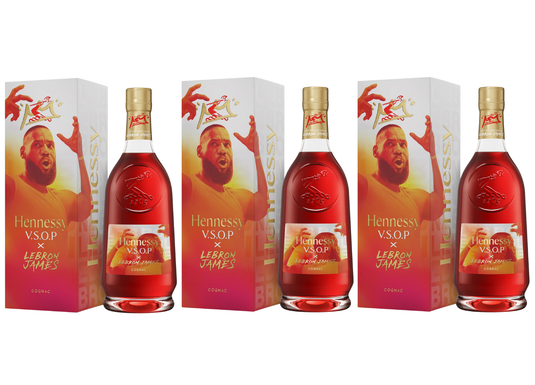 Three Hennessy V.S.O.P x LeBron James Limited Edition Cognac bottles stand before boxes featuring LeBron's raised arm and a bold red-and-yellow design, highlighting this unique Hennessy tribute to the basketball legend.