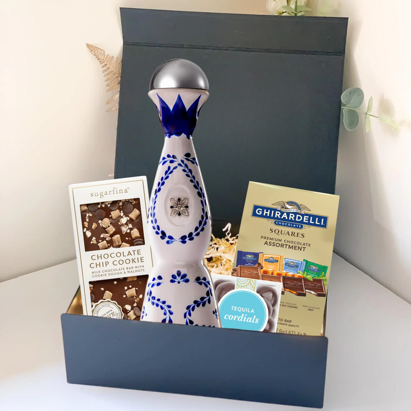 Load image into Gallery viewer, The Premium Tequila Gift Box from Main Street Liquor includes a blue and white ceramic bottle of premium tequila, Sugarfina chocolate chip cookie bites, Ghirardelli chocolate squares, and a small box of tequila cordials.
