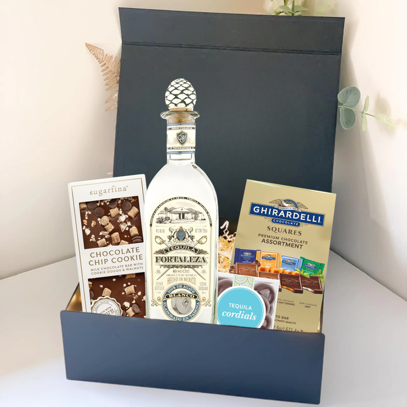 Load image into Gallery viewer, The Premium Tequila Gift Box from Main Street Liquor features Fortaleza tequila, Sugarfina chocolate chip cookie bites, and Ghirardelli chocolate squares, all beautifully arranged against a light background.
