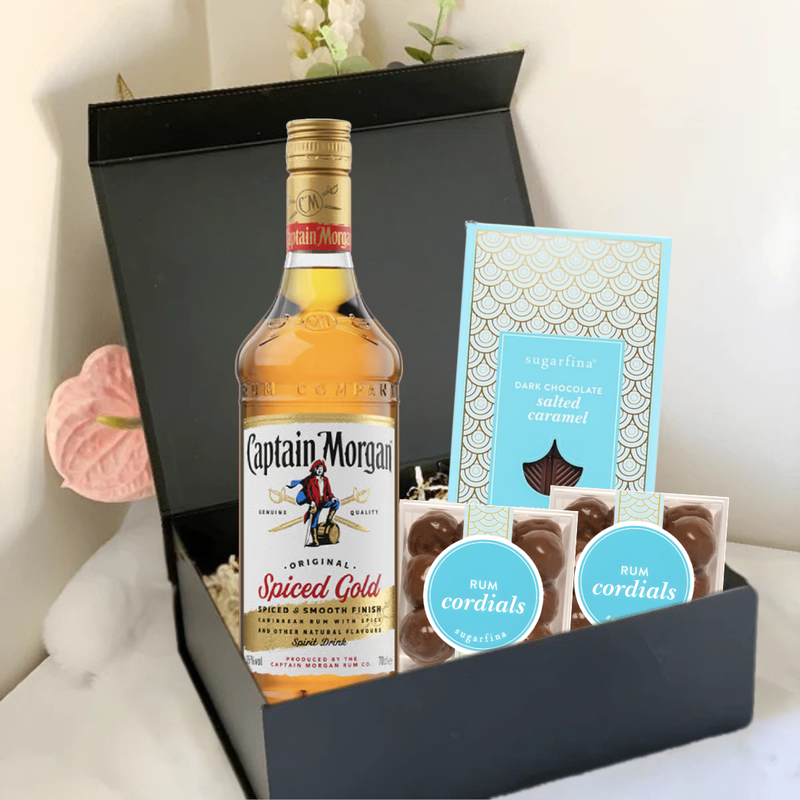 Load image into Gallery viewer, The Premium Rum Gift Box by Main Street Liquor includes Captain Morgan Spiced Gold, Sugarfina Rum Cordials, and dark chocolate sea salt caramels, elegantly presented against a light background.
