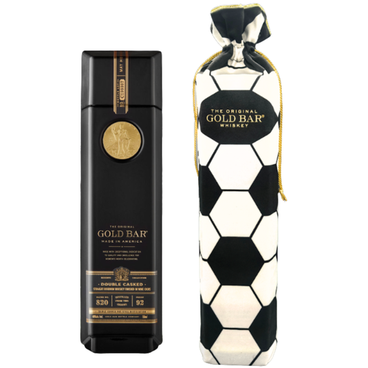 A black and gold bottle of Gold Bar Black Double Cask Bourbon Soccer Bag Edition stands beside a soccer bag edition fabric bag with a gold drawstring, both branded Gold Bar and showcasing this unique double cask bourbon.