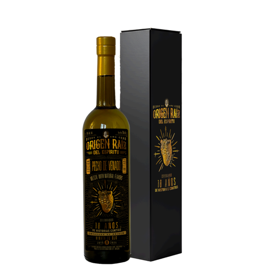 A dark glass bottle of Origen Raiz Pecho de Venado Anniversary Edition Mezcal (PRE-ORDER) stands beside a matching black and gold box, featuring gold lettering, a deer head design, and the label 