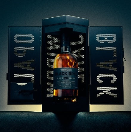 Load image into Gallery viewer, A bottle of Widow Jane Black Opal 20 Year Mizunara Oak Finished Bourbon 99 Proof 750mL inside a black, cabinet-style display box with perforated letters on the open doors.
