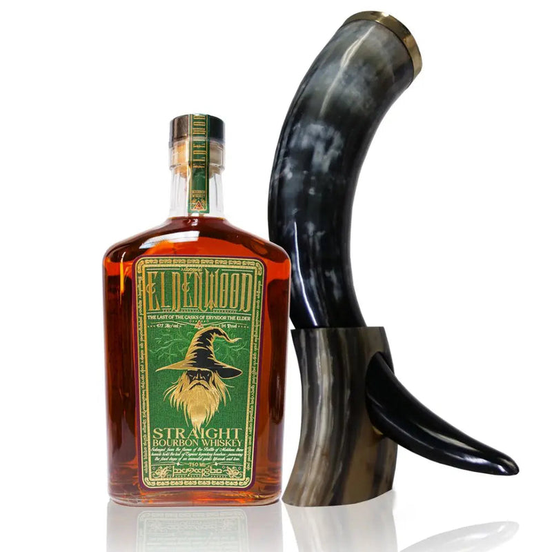 Load image into Gallery viewer, A bottle of Eldenwood Straight Bourbon Whiskey with a green and gold label featuring Eryndor the Elder’s wizard hat, placed beside a polished curved drinking horn on a matching stand.
