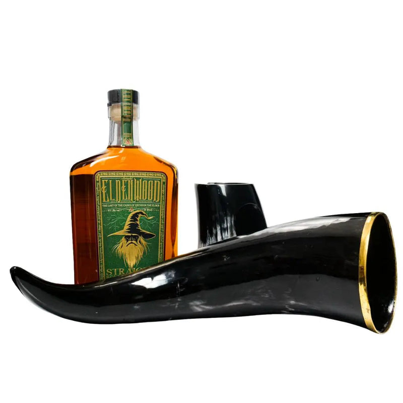 Load image into Gallery viewer, A bottle of Eldenwood Straight Bourbon Whiskey by Eldenwood with a green label featuring Eryndor the Elder, displayed beside a large polished black drinking horn with a gold-trimmed rim.

