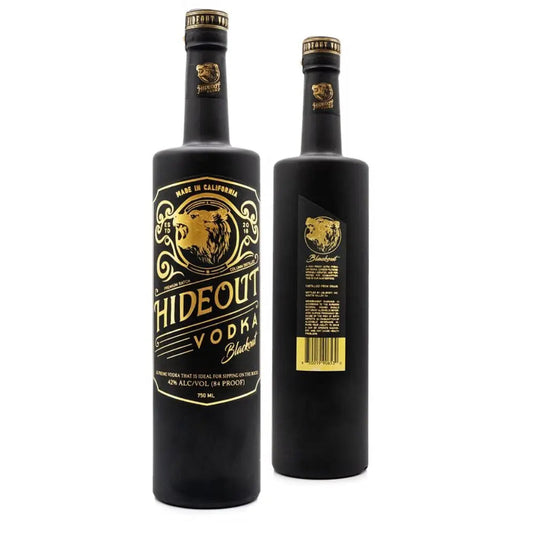 Two black bottles of Hideout Vodka Blackout Edition, one displaying the front label with a bear graphic and gold text, and the other showing the back label with product details and a barcode.