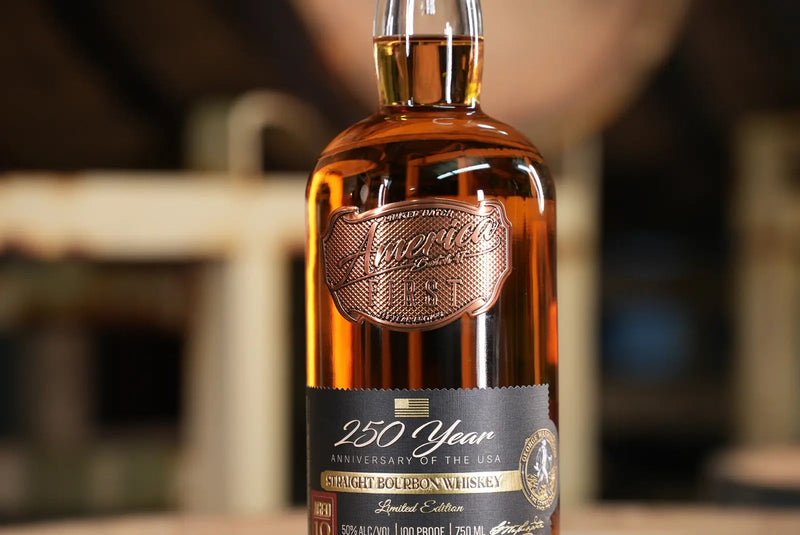 Load image into Gallery viewer, A close-up of an America First 250 Year Limited Edition Bourbon bottle, featuring intricate copper and gold accents and a label highlighting its 10-year aged bourbon, set against a softly blurred background.
