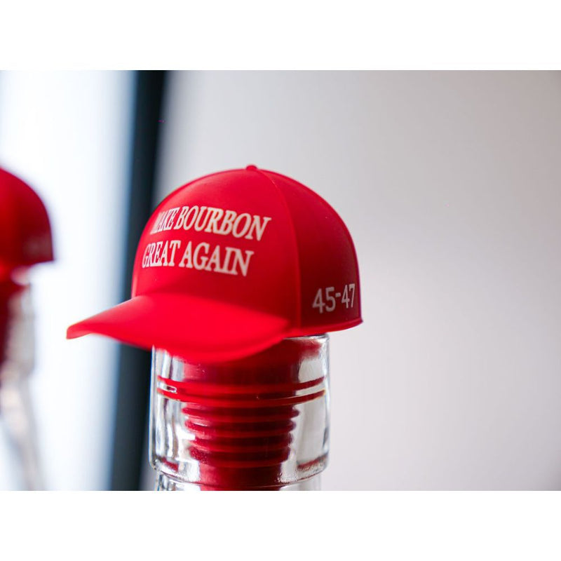 Load image into Gallery viewer, A red "MAKE BOURBON GREAT AGAIN" 45-47 baseball cap tops an America First Straight Bourbon Whiskey bottle, serving as a festive bottle topper and showcasing American craftsmanship.
