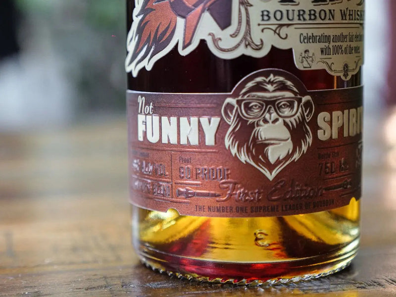 Load image into Gallery viewer, A close-up of the Rocket Man Bourbon Whiskey bottle label shows a chimpanzee in glasses and bold "Rocket Man" branding, with decorative details and political parody elements typical of this limited release.

