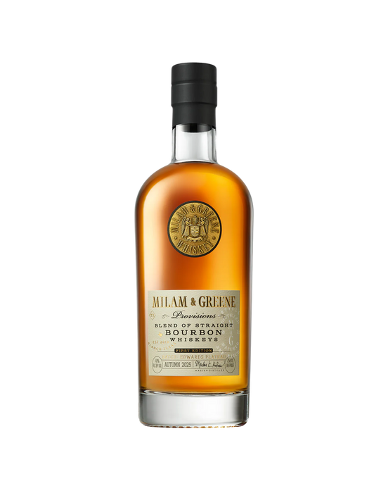 A bottle of Milam And Greene Provisions Bourbon First Edition Autumn 2025 features a black cap, gold seal near the neck, and a label reading “Milam & Greene Bourbon Whiskey.” This Texas craft whiskey glows with an amber hue.