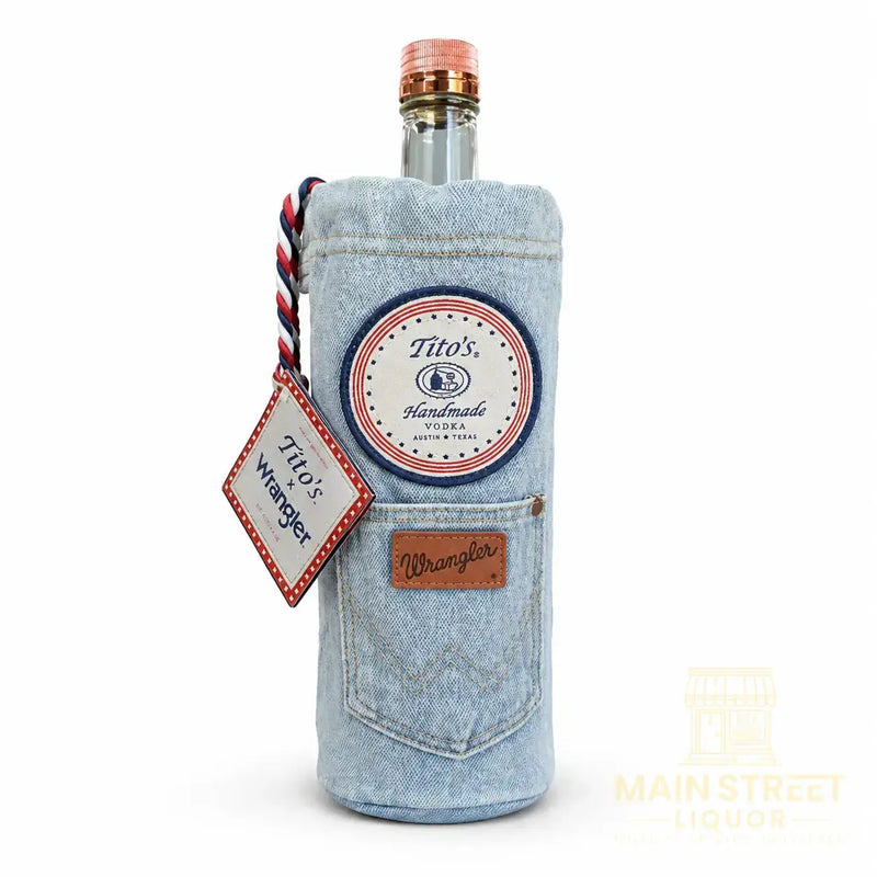 Load image into Gallery viewer, Introducing the Tito’s X Wrangler® Limited Edition 1L by Tito’s Vodka—a special gift set featuring a 1-liter bottle of Tito’s Vodka wrapped in a light blue Wrangler denim sleeve. This classic blue jeans-inspired sleeve is detailed with a patch, braided tag labeled “Titos x Wrangler,” a small front pocket, and topped off with an authentic-looking leather-like Wrangler label above the pocket for an extra-special touch.
